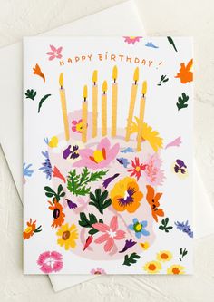 a birthday card with flowers and candles on it, sitting on top of a table