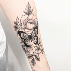 a woman's arm with a butterfly and flowers tattoo on the left inner arm