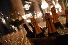 several bottles of champagne sitting in a bucket on top of a table with wine glasses