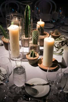 the table is set with candles, plates and succulents for dinner guests