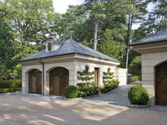 two garages in the middle of a driveway with trees and bushes around them on either side