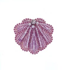 a pink and purple brooch with beads on it's side, sitting in front of a white background