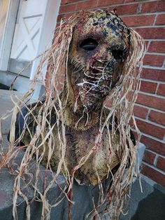 a creepy looking statue with long hair on it's head and eyes covered in paint