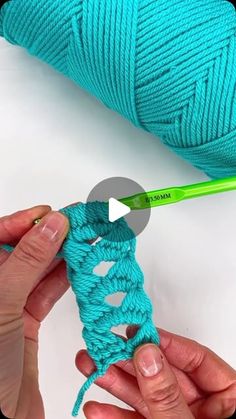 someone crocheting the ends of a blue yarn ball with a green crochet hook