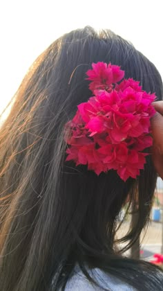 a woman with long black hair and pink flowers in her hair