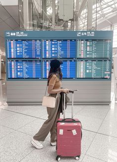 a woman is pulling her luggage through an airport with the check in area behind her