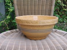 a brown bowl sitting on top of a wicker chair next to a planter