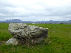 a large rock sitting on top of a lush green field