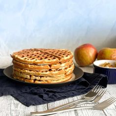 a stack of waffles sitting on top of a plate next to some apples