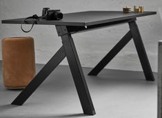 a black table with a camera on it next to a chair and vase in the background