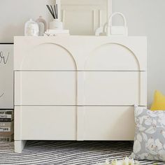 a white dresser sitting on top of a striped rug