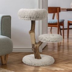 a cat scratching tree in the middle of a living room with two chairs around it