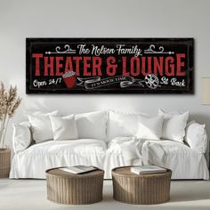 a living room with white furniture and pillows on top of the couch, in front of a wooden sign that says theater & lounge