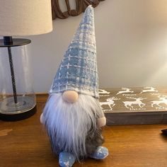 a stuffed toy gnome sitting on top of a table next to a lamp and phone