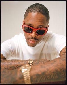 a man with tattoos and red sunglasses sitting at a table