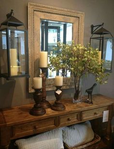 a wooden table topped with candles next to a mirror