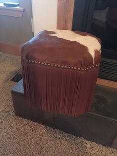 a brown and white ottoman sitting on top of a floor next to a fire place