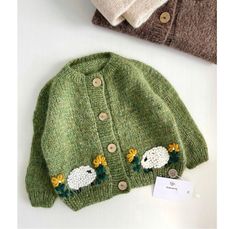 two knitted sweaters with sheep on them, one is green and the other is brown