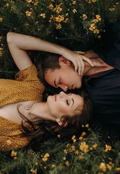 two people laying in the grass with their heads touching each other's foreheads