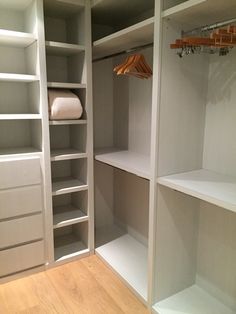 an empty walk in closet with white shelves