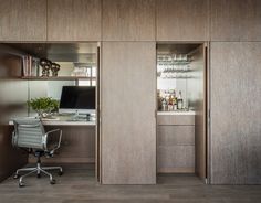 an office area with a desk, computer and shelves on the wall next to it