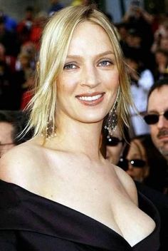 a woman with blonde hair and blue eyes smiles at the camera while standing in front of a crowd