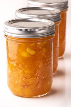 four mason jars filled with pickles on a white surface