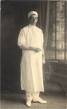 an old black and white photo of a man in a doctor's outfit standing next to a window