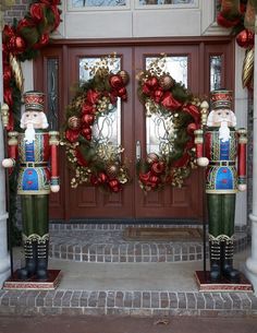 two christmas nutcrackers standing in front of a door with wreath on it