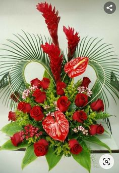 a vase filled with red flowers and greenery