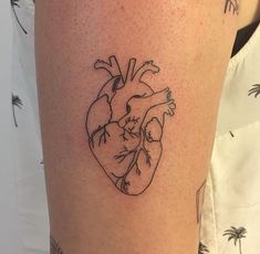 a small tattoo of a heart on the right leg, with palm trees in the background