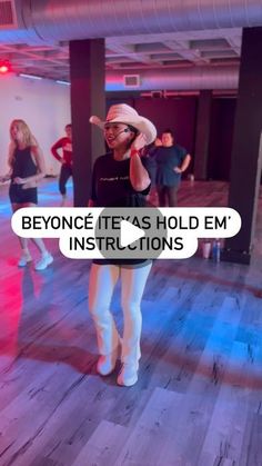 a woman wearing white pants and a cowboy hat is talking on her cell phone in an empty room