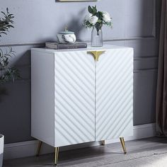 a white cabinet sitting next to a vase with flowers