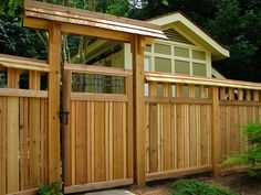 a wooden fence with two doors and a shed in the back ground, surrounded by trees