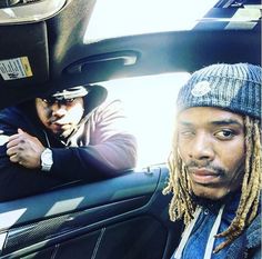 two men sitting in the back seat of a car, one with dreadlocks