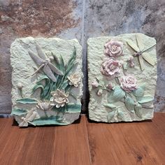 two pieces of stone with flowers and dragonflies on them