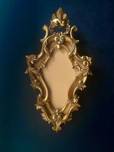 an ornate gold framed mirror on a blue wall with the reflection of it's own image