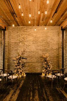 two chairs with flowers and candles are set up in front of a brick wall for a wedding ceremony