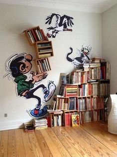 a room with bookshelves, shelves and cartoon characters painted on the wall behind them