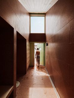 a person walking down a long hallway between two walls with open windows on each side