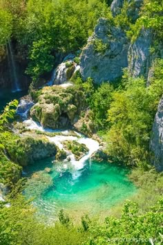 a river running through a lush green forest filled with lots of rocks and water flowing down it