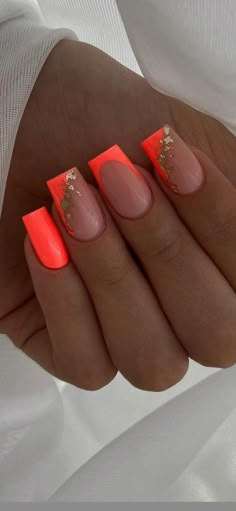 a woman's hand with neon orange and gold nails