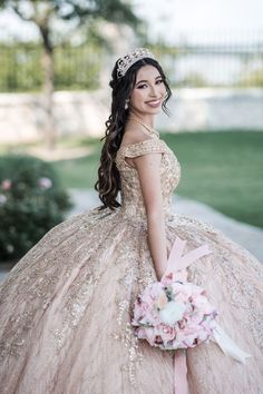 a woman in a ball gown holding a bouquet and posing for the camera with her hand on her hip