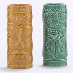 three green and gold vases with faces on the sides, one is made out of clay