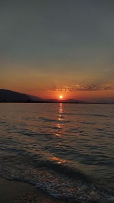 the sun is setting over the water at the beach