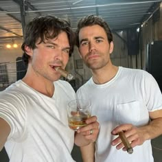 two men standing next to each other holding cigars