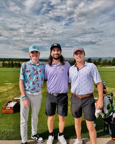 three men standing next to each other on a golf course