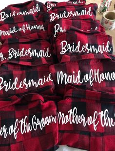 several red and black flannel shirts with names on them sitting on a table