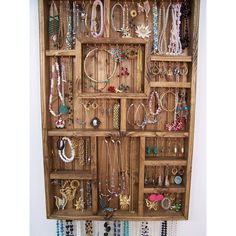 a wooden shelf filled with lots of necklaces and bracelets hanging on it's sides