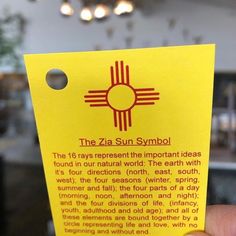 a person holding up a yellow card with the words, the zia sun symbol